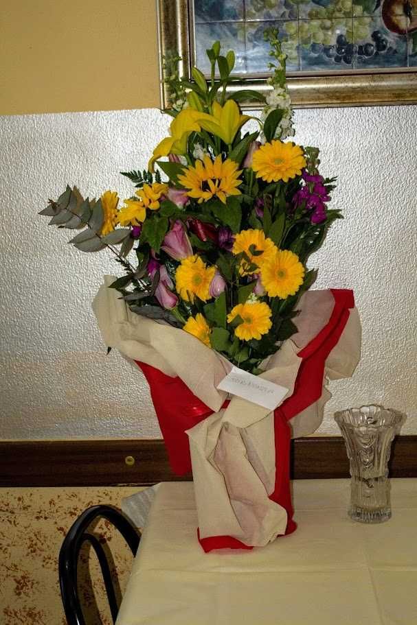 Fiore decorativo con girasoli, rose e fiori colorati in bouquet elegante, decorazione floreale per eventi e occasioni speciali, in vaso su tavolo, stile raffinato e vibrante.