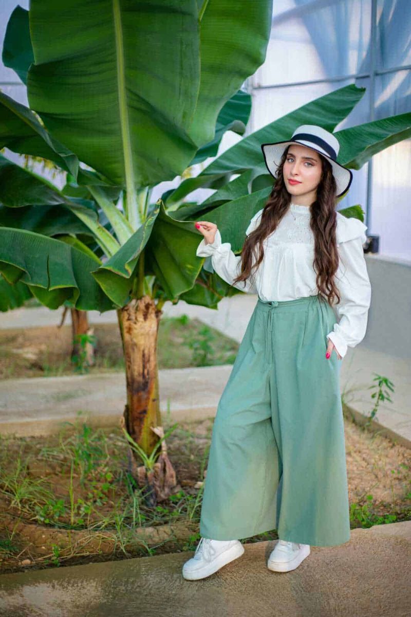 Come abbinare i pantaloni baggy: idee e consigli per ogni look 5 Banana plant nell'ambiente di una serra, donna giovane con cappello e abiti alla moda, moda sostenibile, giardinaggio urbano, verde lussureggiante, stile casual elegante, moda eco-friendly, accessori di moda legge, oggetti di moda e natura.