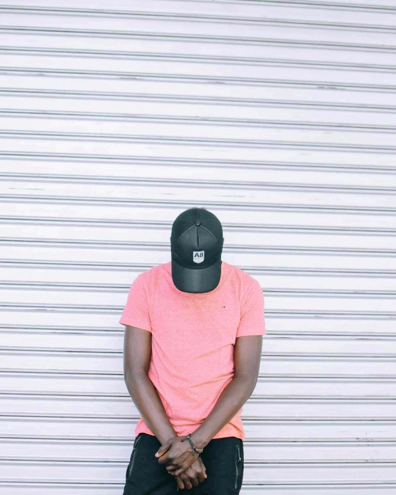 Beginner’s Workout Wardrobe: 6 Capi di Abbigliamento Sportivo Indispensabili per l’Uomo 2 A8 cappellino, persone giovani con abbigliamento casual, street style, sfondo di serranda metallica, moda urbana, stile casual, outfit estivo, look alla moda, tendenze streetwear, accessori moda, rap, hip hop, cultura di strada, self-expression, giovani artisti, fashion statement.