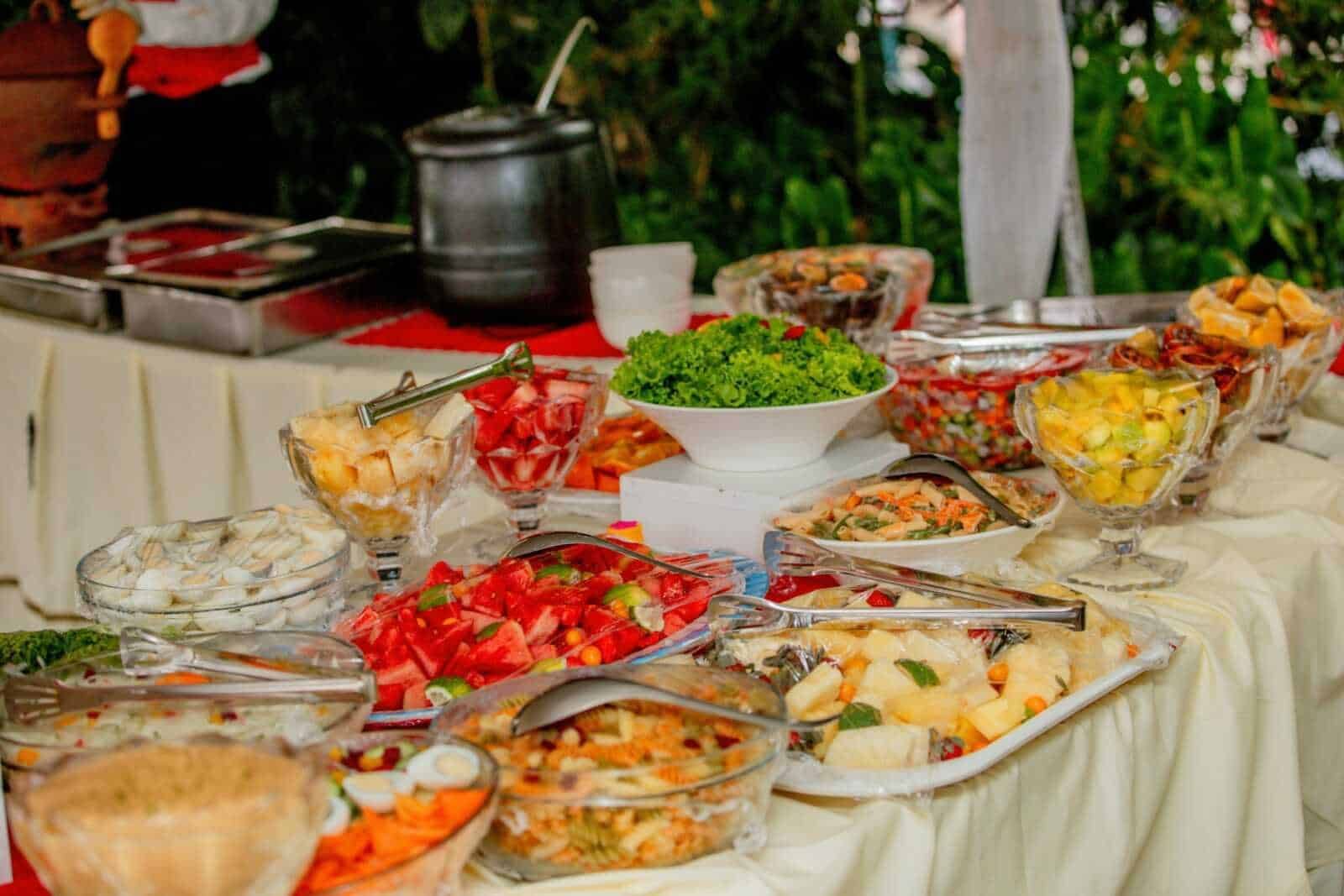 Fresca esposizione di insalate di frutta e verdura fresche in un buffet all'aperto, ideale per eventi estivi, con ricette salutari e colorate.