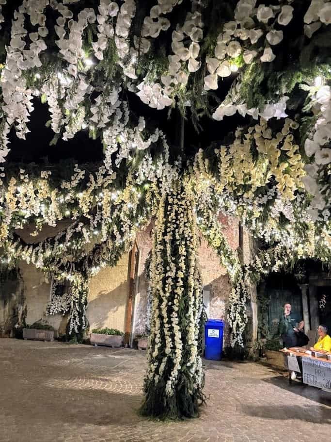 Festa dei fiori Monte Isola 2025 dopo 10 anni 3 Un albero decorato con fiori bianchi e luci LED in un evento all'aperto, creando un'atmosfera magica e romantica. Perfetto come decorazione floreale per matrimoni e occasioni speciali.