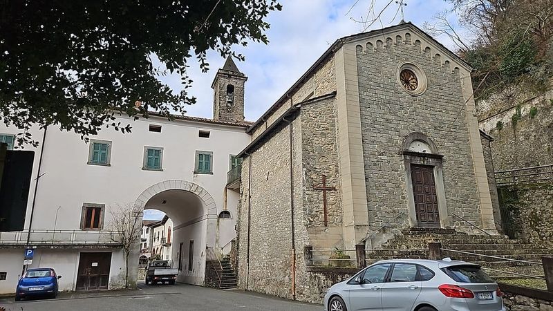 Bagnone cosa visitare nel centro storico 2 Castello malaspina: Vecchia chiesa in pietra a Montecchio, Italia, con ingresso principale e dettagli architettonici storici, circondata da veicoli e suggestivo paesaggio urbano.