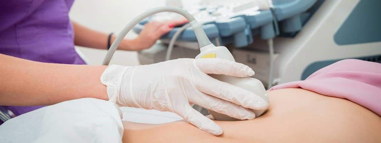 Ecografia in corso sulla pancia di una paziente, con medico che utilizza sonda per diagnosi medica, in ambiente clinico.