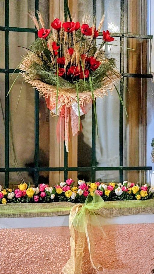 Festa dei fiori Monte Isola 2025 dopo 10 anni 9 Fiori rossi e gialli decorativi con nastri colorati per occasioni speciali, ornati su una ringhiera con decorazioni floreali e nastri di tessuto, creando un elegante ambiente festivo.
