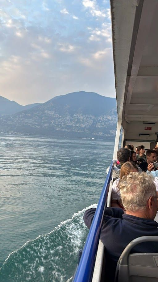 Festa dei fiori Monte Isola 2025 dopo 10 anni 11 Passeggeri su un battello che naviga su un lago ai piedi di montagne, con cielo nuvoloso, atmosfera di viaggio e relax sulla barca.