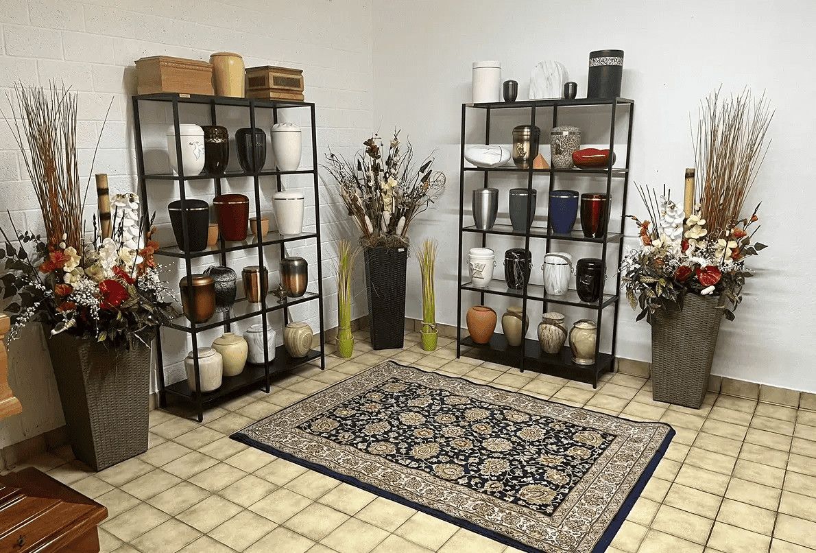 Vasi decorativi in ceramica e vasi in metallo su scaffali neri, disponibili in vari colori e materiali, con composizioni floreali e arredo di interni eleganti.