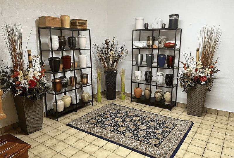 Cosa fanno le onoranze funebri: consigli utili 5 Vasi decorativi in ceramica e vasi in metallo su scaffali neri, disponibili in vari colori e materiali, con composizioni floreali e arredo di interni eleganti.