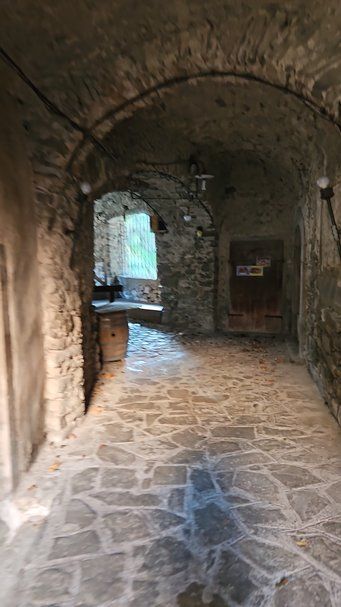 Un corridoio in pietra antica con arcate in un edificio storico, ambiente rustico e suggestivo, perfetto per apprezzare l'architettura tradizionale e il fascino del passato.