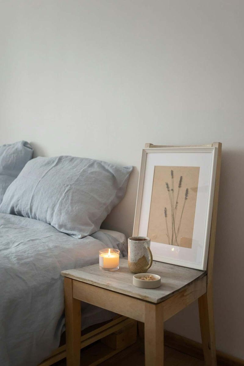 10 vantaggi delle candele aromatiche per migliorare la salute 4 10 vantaggi delle candele aromatiche per migliorare la salute. Luminosità morbida con candela accesa, decorazioni minimaliste e quadro con fiori essiccati sul comodino in legno per un'atmosfera rilassante e accogliente.