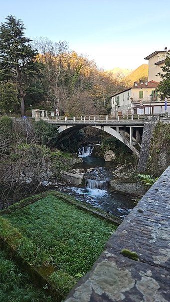 Tranquillo ponte in pietra sopra un fiume naturale circondato da natura e case, ideale per appunti sul blog sulla bellezza dei paesaggi italiani e il turismo sostenibile in ambienti rurali.
