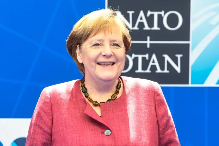 10 Donne più potenti della Storia: simboli di Forza 12 Angela Merkel in un evento internazionale, sorridente davanti a un backdrop NATO, rappresenta leadership politica e impegno diplomatico.