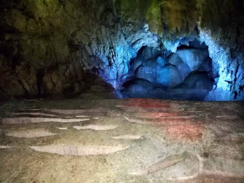 La Grotta di Oweynagat, la porta degli spiriti nella mitologia celtica 3 La Grotta di Oweynagat, la porta degli spiriti nella mitologia celtica. Immagine di una grotta con rocce illuminate da luci blu e verdi, mostrando dettagli della parete rocciosa e una Morse di pietra al primo piano, ideale per esplorazioni sotterranee e turismo di speleologia.