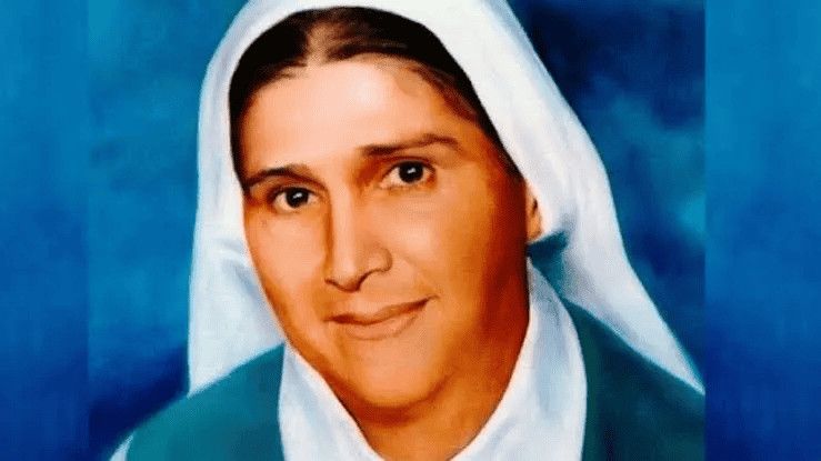 10 Donne più potenti della Storia: simboli di Forza 10 Immagine di una donna vestita con un abito bianco e un velo blu, che ricorda un'iconica rappresentazione religiosa, simbolo di speranza e fede.
