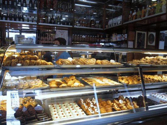 Pasticceria assortita con dolci freschi e croissant in esposizione in una panetteria artigianale italiana.