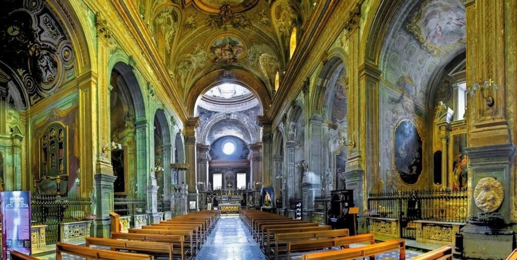 Una chiesa barocca artistica con archi elaborati, affreschi e decorazioni d'oro, caratterizzata da un ambiente sacro ricco di dettagli artistici e un'atmosfera spirituale.