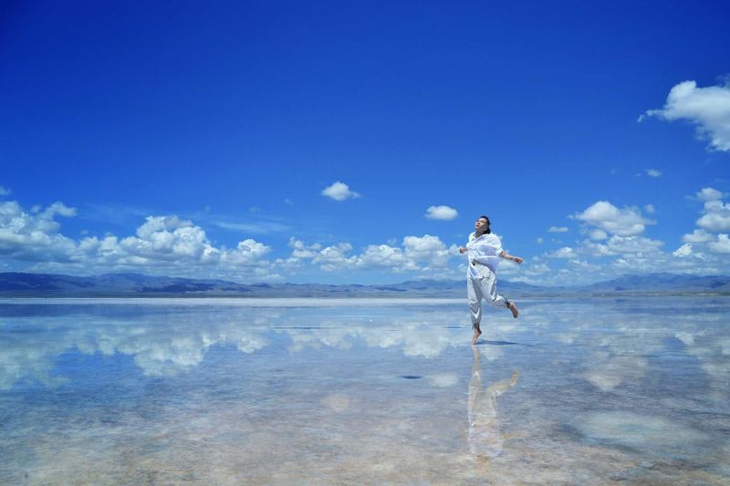 Prenota ora le tue vacanze per trovare le occasioni migliori 4 Nuvola riflessa su salaronda salata con donna che danza in abbigliamento bianco sotto cielo blu.