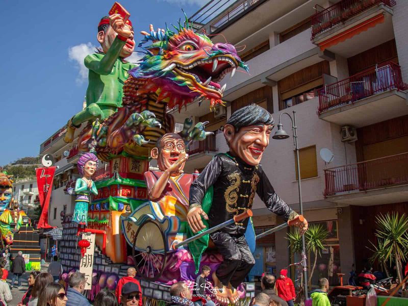 Il Gran Carnevale Maiorese 2026: Sogni in Cartapesta sulla Costiera Amalfitana 8 Carro allegorico con figure di cartapesta e personaggi tradizionali del Carnevale Maiorese, in una strada della Costiera Amalfitana, durante la sfilata.