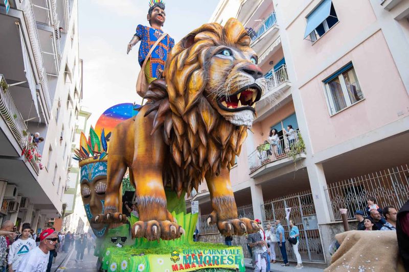 Il Gran Carnevale Maiorese 2026: Sogni in Cartapesta sulla Costiera Amalfitana 5 Grande leone di cartapesta con figura umana in costume colorato, parte del Carnevale Maiorese 2026 sulla Costiera Amalfitana.