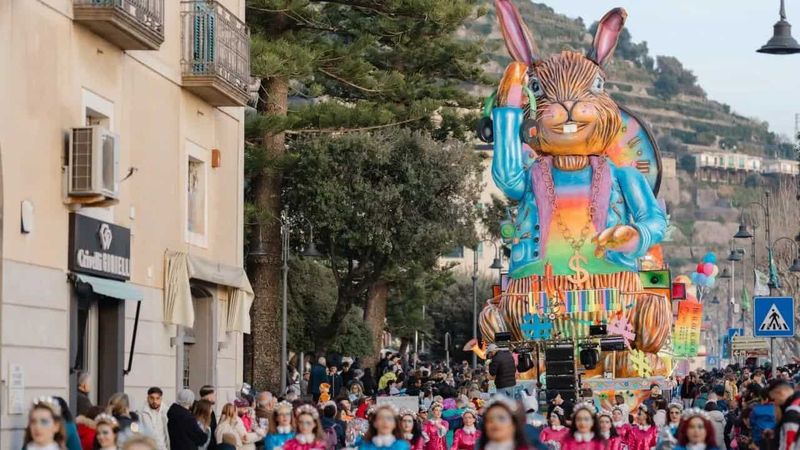 Il Gran Carnevale Maiorese 2026: Sogni in Cartapesta sulla Costiera Amalfitana 9 Grande carro di cartapesta raffigurante un coniglio colorato durante il Carnevale Maiorese 2026 sulla Costiera Amalfitana, con folla di visitatori e decorazioni festive.