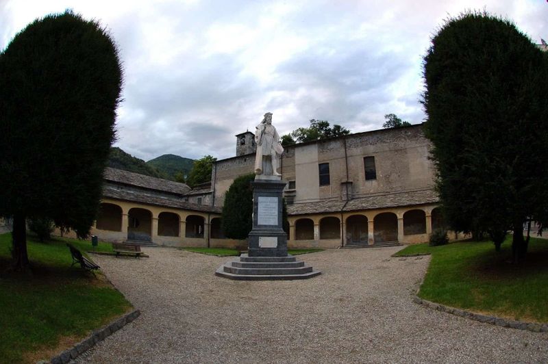 8 attrazioni a Varallo e dintorni in Valsesia 10 Statua storica nel cortile di un edificio storico con alberi e cielo nuvoloso.