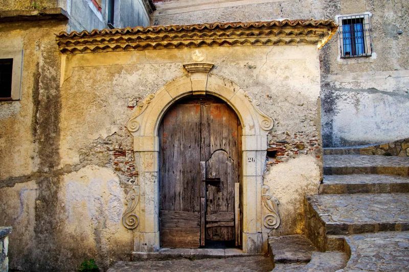 Dalle spiagge dorate della Puglia alle scogliere della Calabria, alla scoperta di un Sud che incanta 6 Portale in pietra e legno in un edificio storico del Sud Italia.