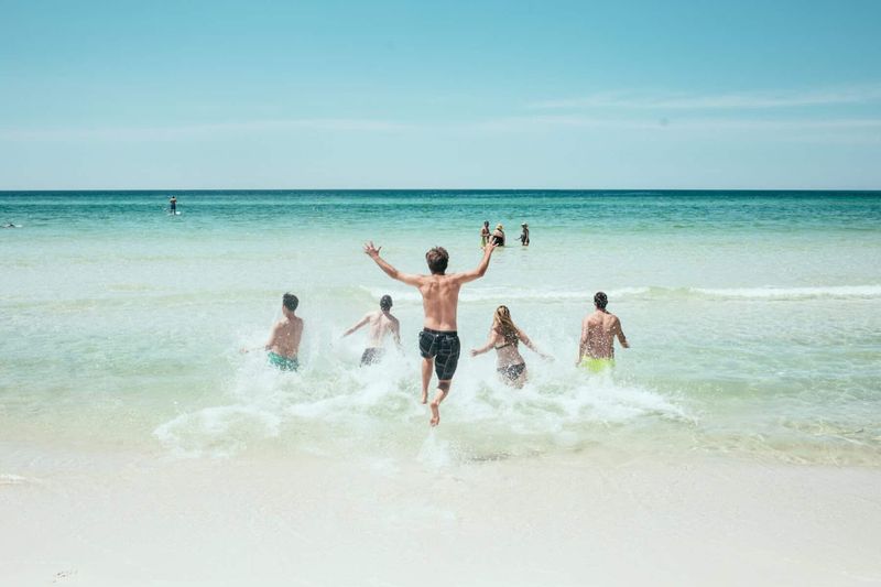 Consigli per le vacanze al mare 6 Consigli per le vacanze al mare. Gruppo di persone che si diverte in spiaggia con il mare e il cielo azzurro sullo sfondo, ideale per contenuti estivi e vacanze al mare.