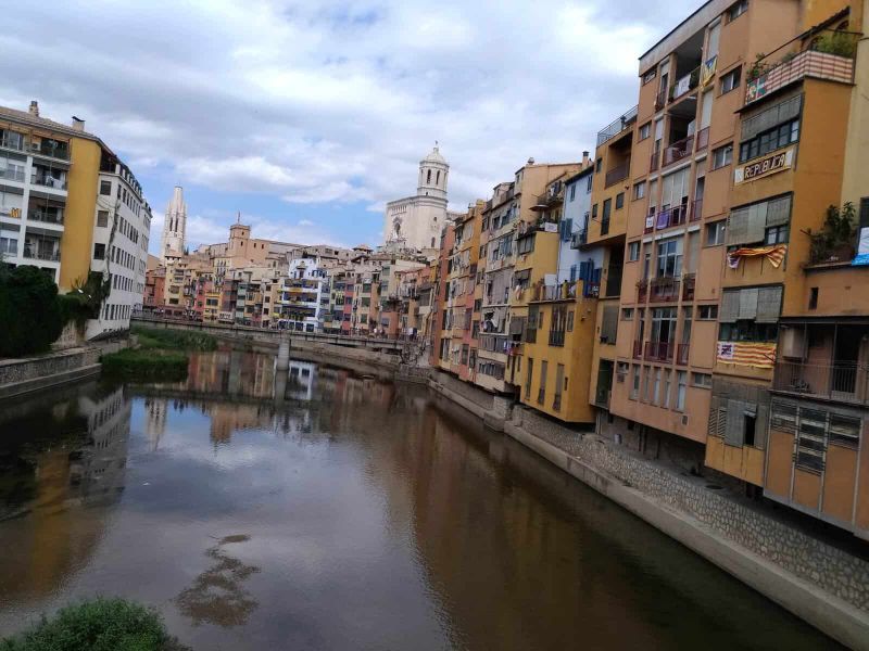 Cosa vedere a Girona in un giorno 5 Vista panoramica di Girona con il fiume Onyar e edifici colorati lungo le rive, con chiese storiche sullo sfondo.
