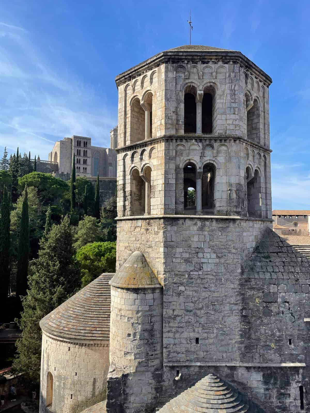 Campanile medievale di Girona con archi e finestre, simbolo della città catalana, visibile contro un cielo azzurro.