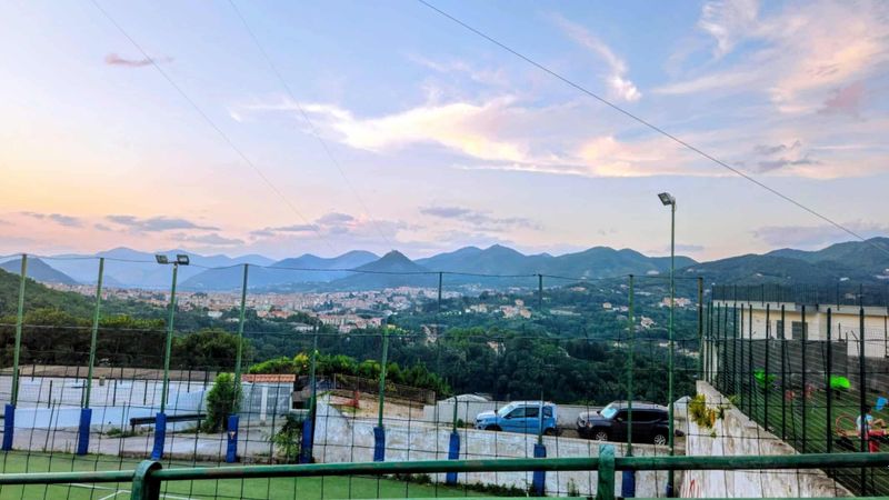 Festa Limoni Dragonea 2026: menù, come arrivare 7 Vista panoramica di una città circondata da montagne con cielo al tramonto, lampioni e parcheggio in primo piano.