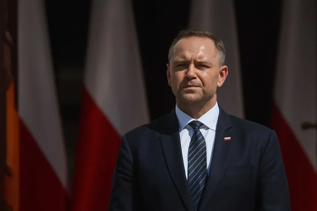 Президент Польши Кароль Навроцкий стоит возле польских флагов