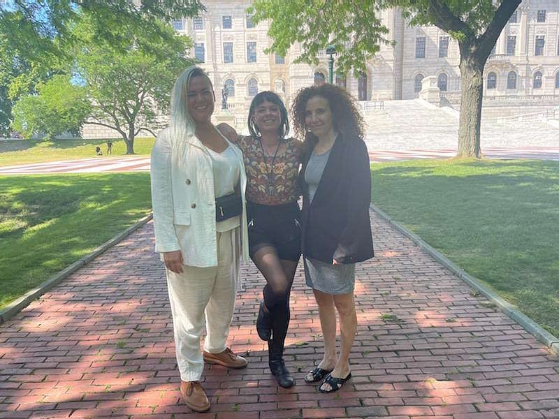 J. Leigh Oshiro-Brantly, Henri June Bynx, and Alison Kolins stand in front of the Rhode Island State House.