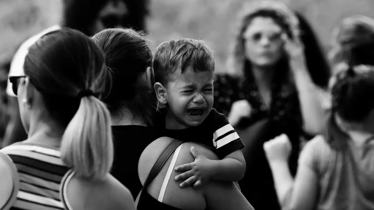 Toplum içinde gelişim çağındaki bir çocuk, annesinin kucağında ağlıyor