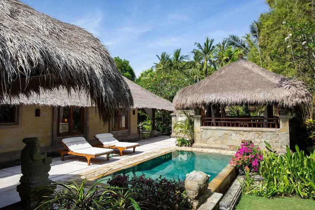 small resort pool surrounded by grass covered buildings