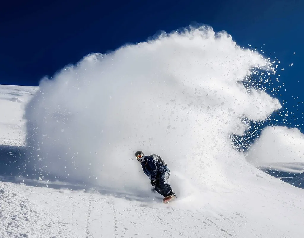snowboarder with snow plume behind him