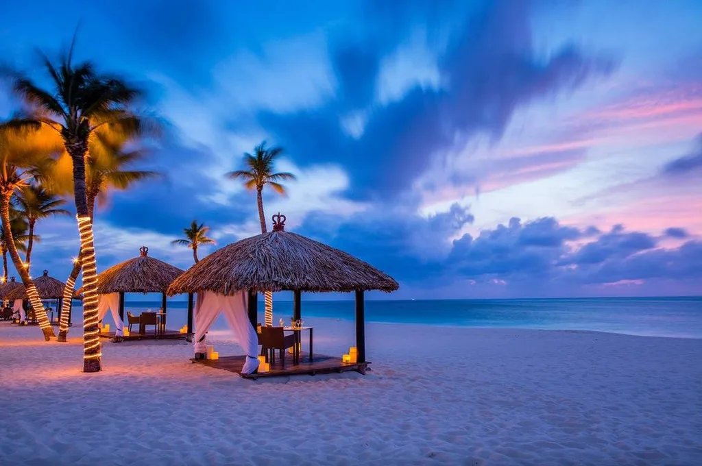 huts on white sand beach at sunset