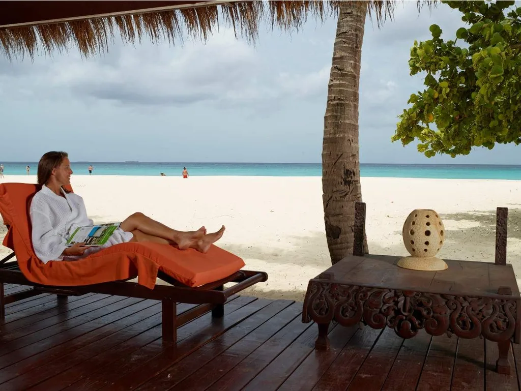 woman laying on orange lounge chair under shade on white sand beach