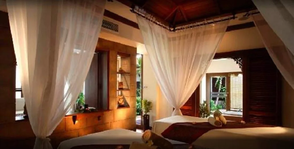 resort room with wood wall and bed surrounded by white curtains