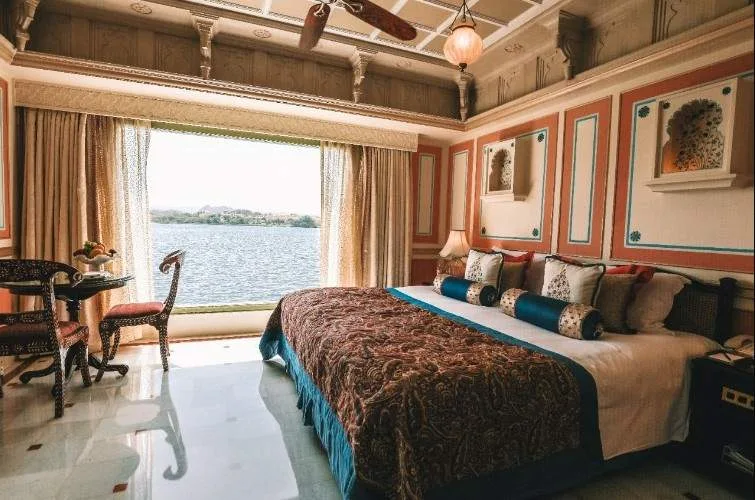 large bed with large open window looking out on water