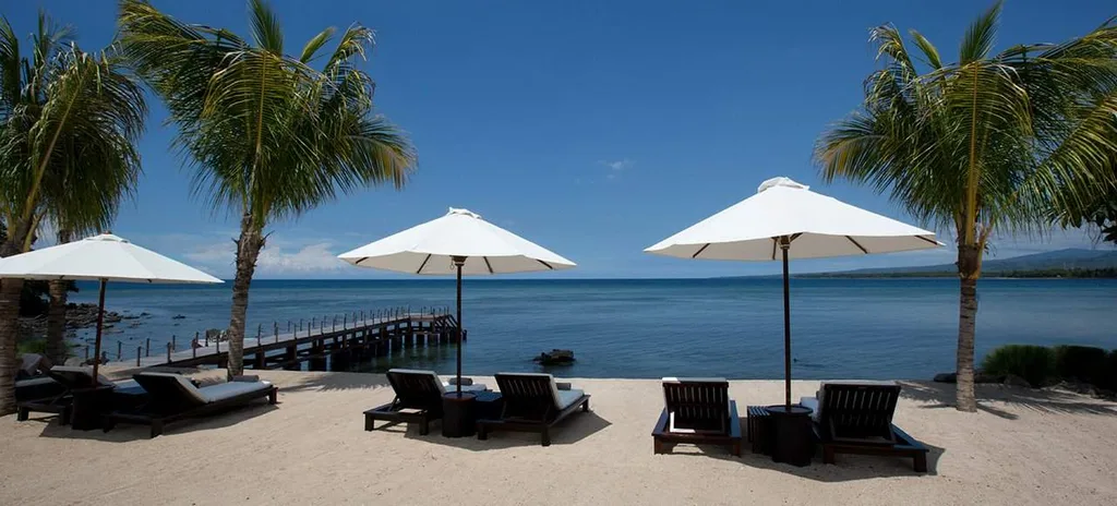 beach lounge chairs under white umbrellas on the beach