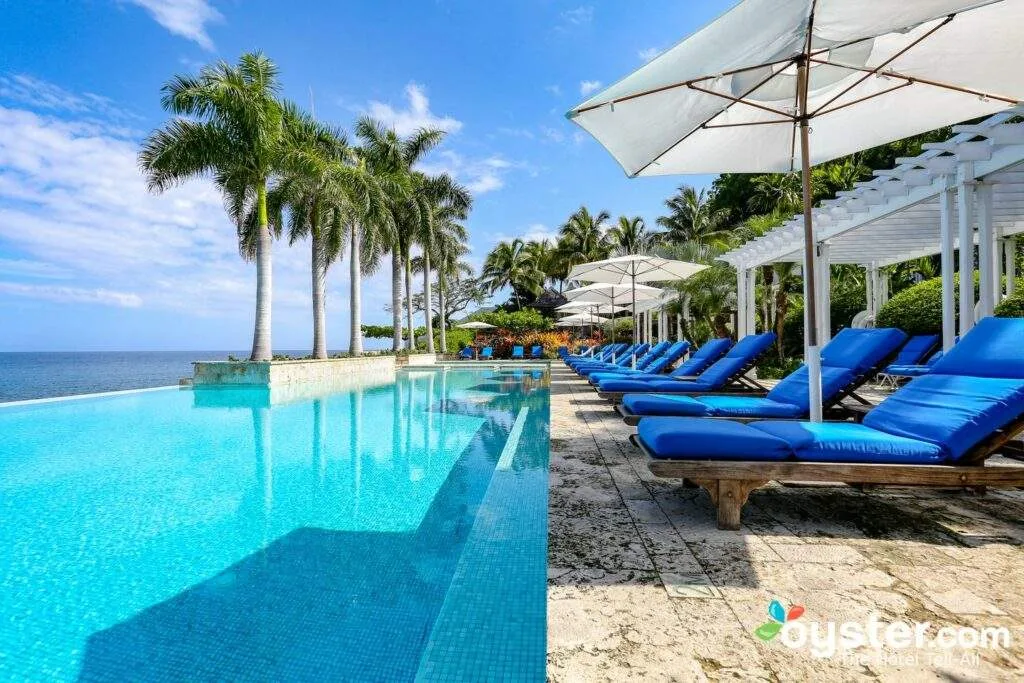 row of blue beach recliners in front of pool and palm trees