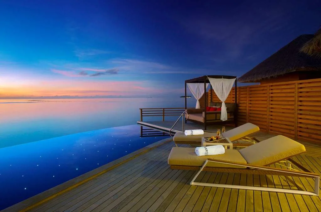 folding lawn chairs on deck facing water at sunset