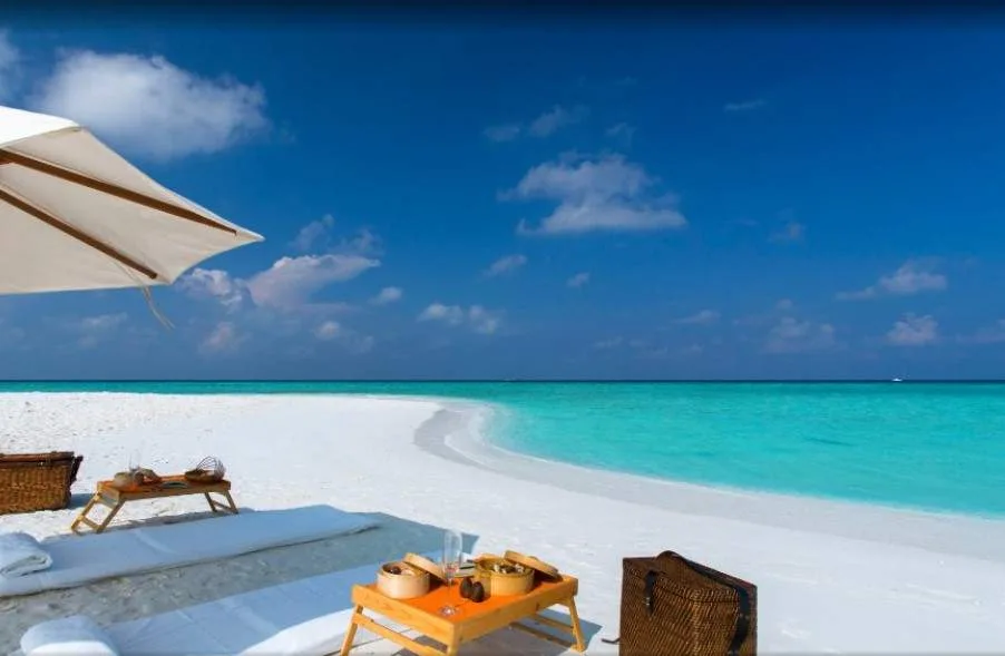 white sand beach with folding beach chair with umbrella