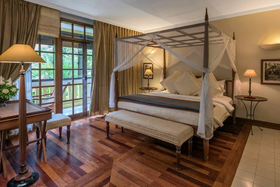 covered bed with wood floor with windows facing trees