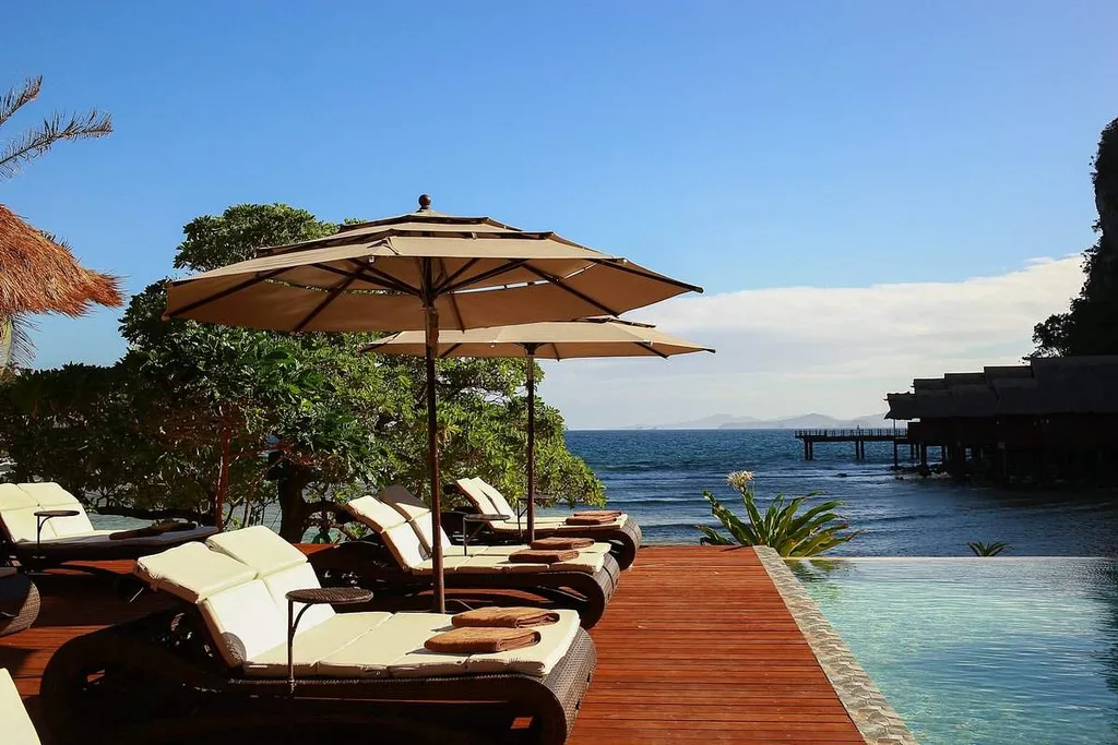 lawn chairs under umbrellas in front of infinity pool