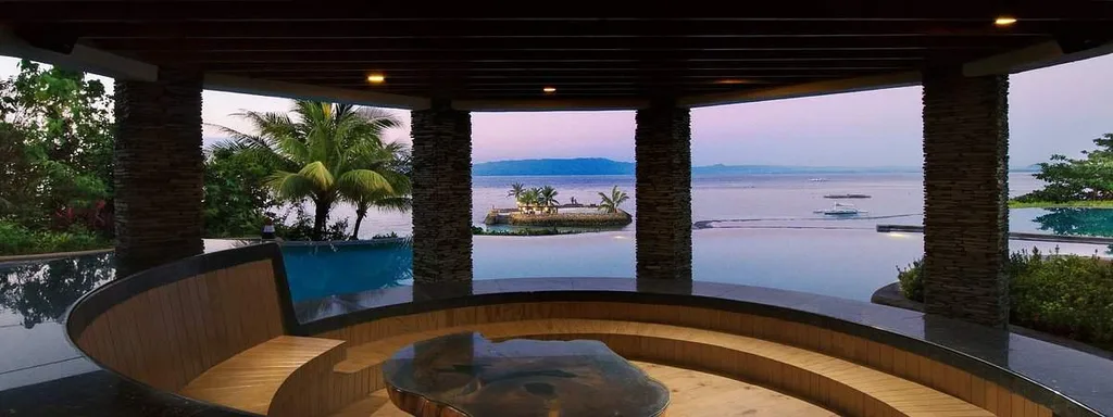 resort room with floor to ceiling windows in semi circle looking out at ocean