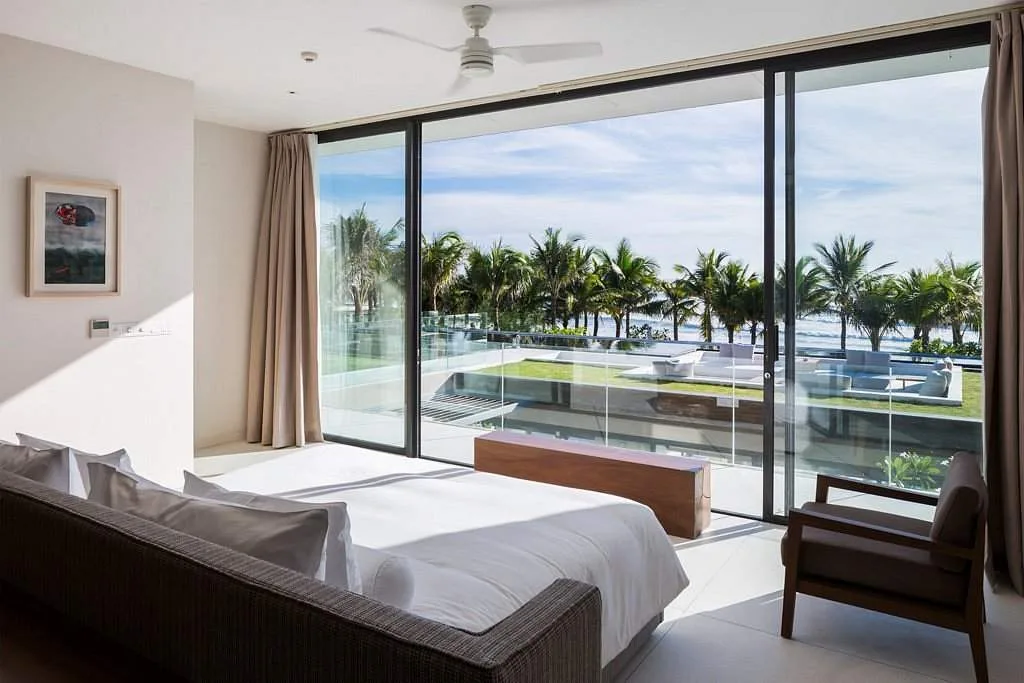 white bed in resort looking out to palm trees