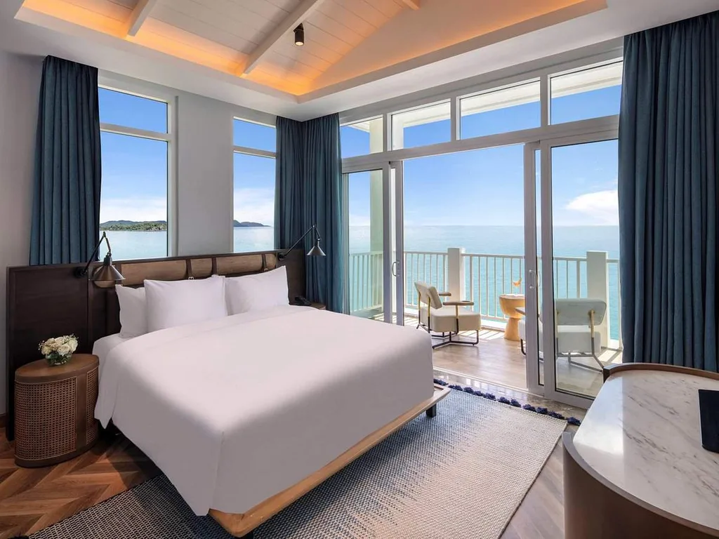 resort room with floor to ceiling windows behind bed