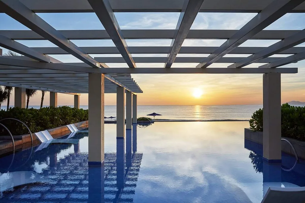 sun setting on ocean in front of infinity pool