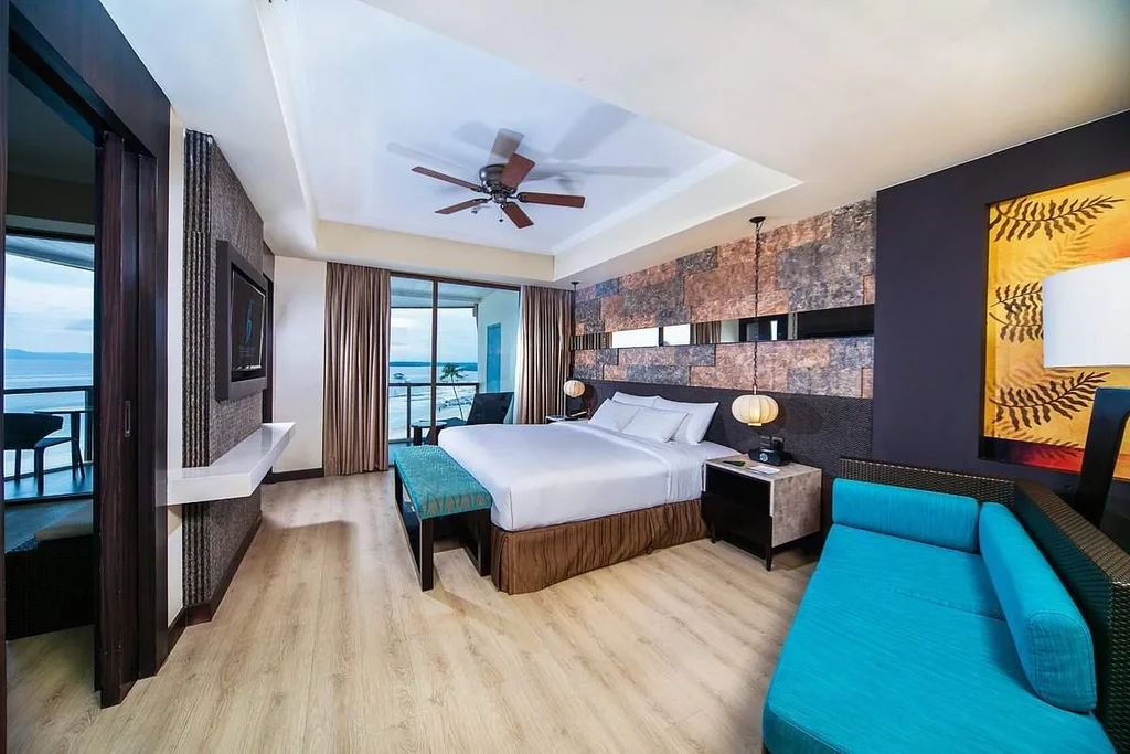resort room with blue couch white bed and ceiling fan