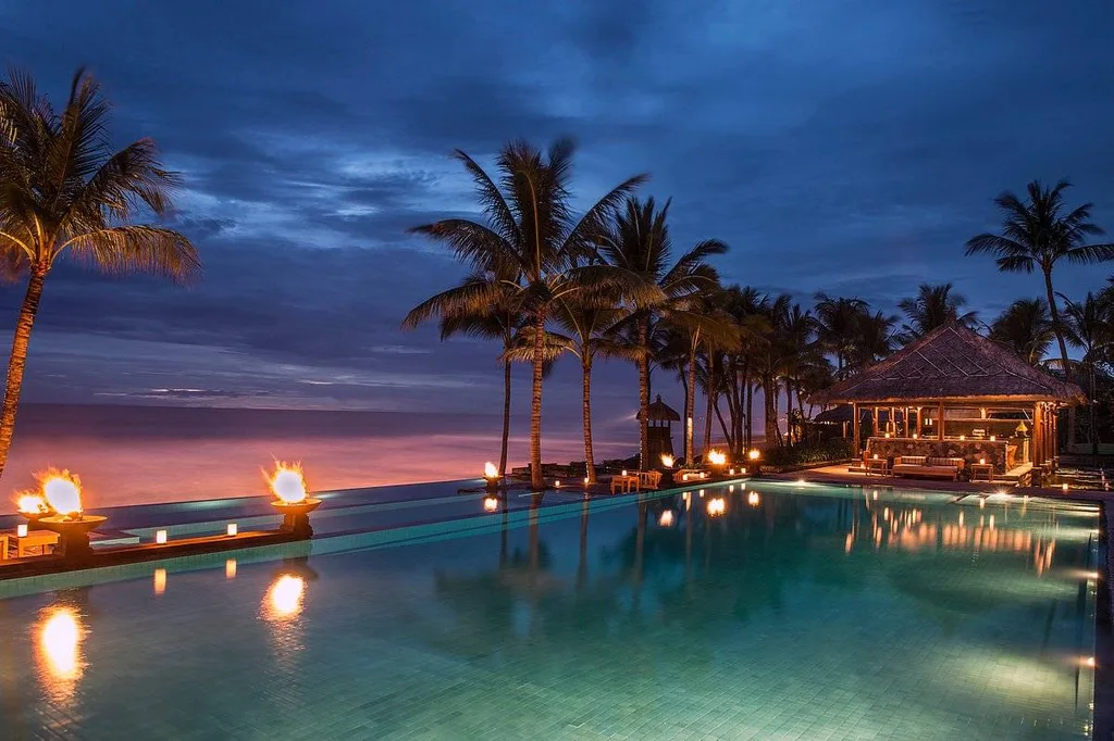 lighted pool with palm trees at beach at night